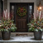 Two winter porch pots with spruce, red twig dogwood, birch branches, pinecones and lights flanking a front door